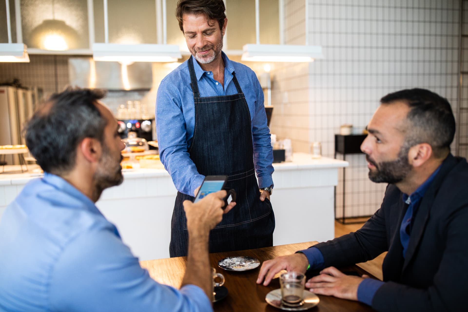 Atendente de cafeteria finalizando um pagamento por aproximação no balcão com cliente